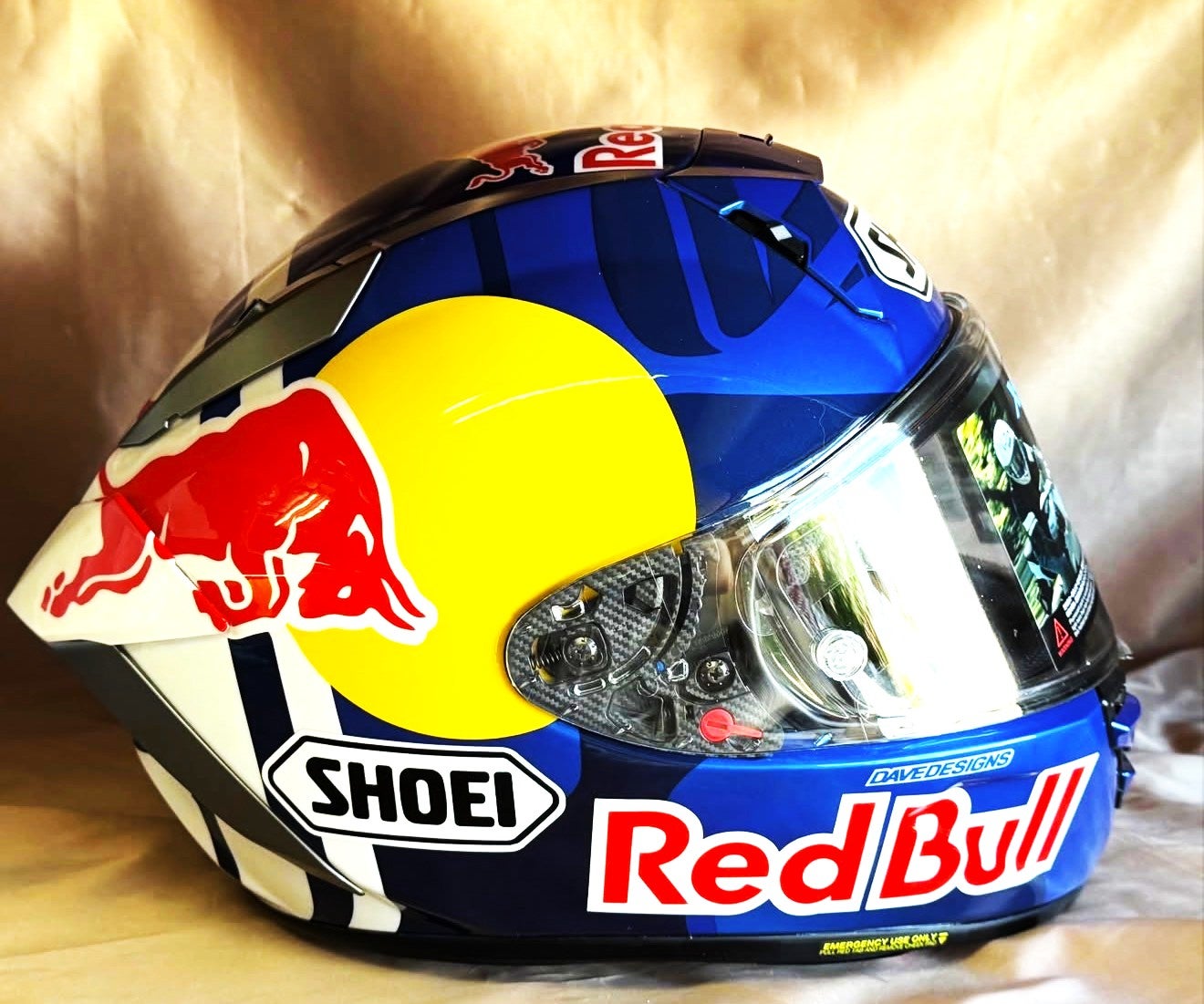 青と紺の配色に黄色の円、白く縁取った赤い牛とRed Bullの文字を配したSHOEI X15ヘルメットのカスタムペイント